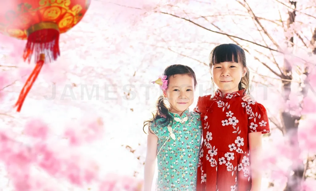 
Happy sisters celebrating chinese new year among blooming pink flowers