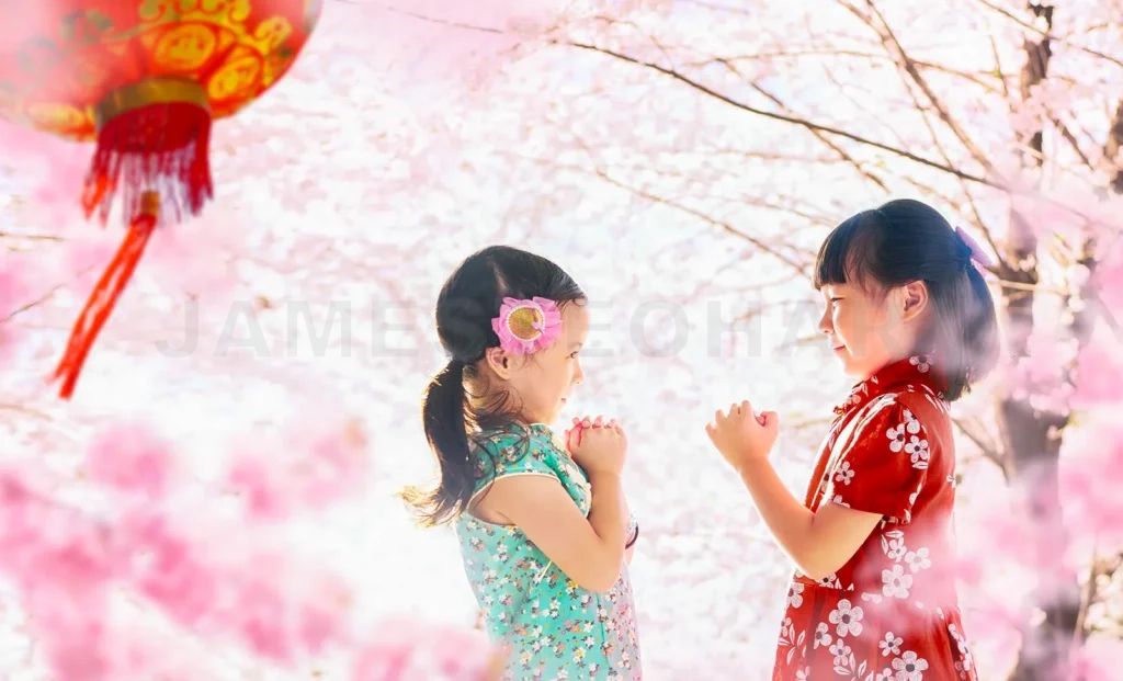 
Two adorable girls celebrate chinese new year among blooming pink flowers