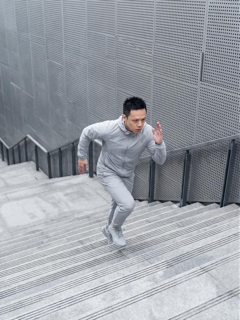 
Asian athlete training running up urban stairs