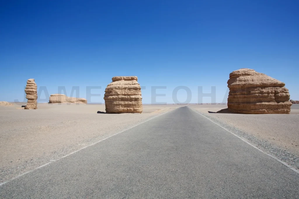 
Long Empty Asphalt Road In Desert With Strange Shape Of The Stone And Clear Blue Sky