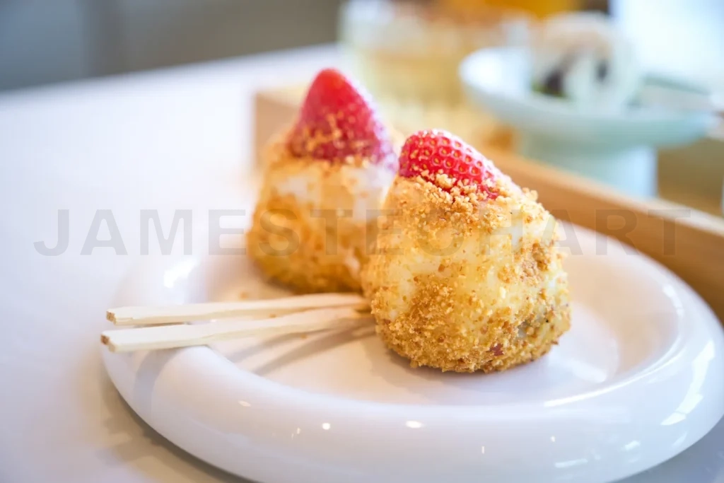 
Two pieces of daifuku mochi topped with strawberries are sitting
