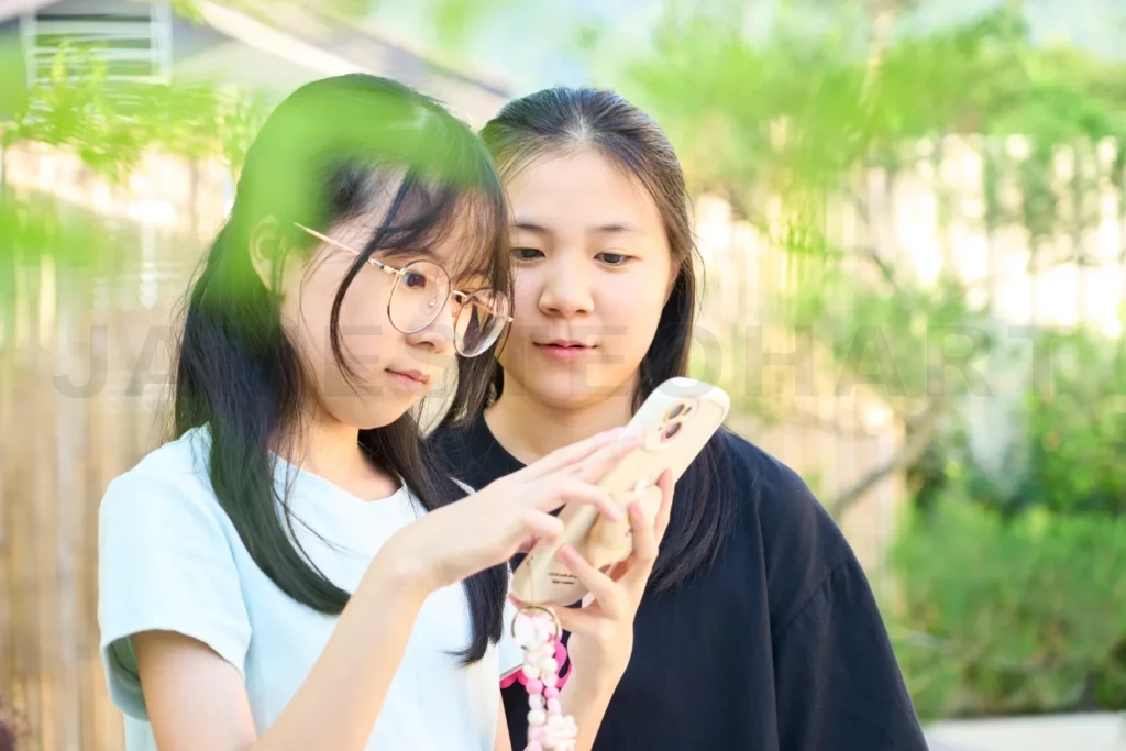
Two girls are using a smartphone in a park