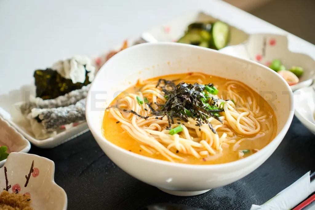 
Steaming bowl of japanese ramen noodles being served with side d
