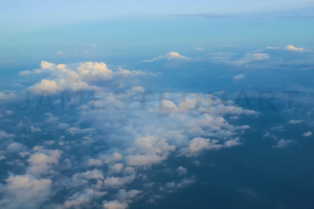 
Fluffy white clouds covering earth from airplane window at sunset