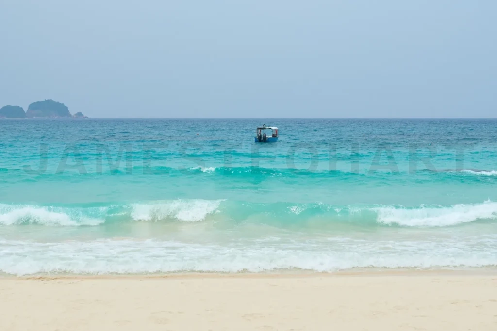
Small motor boat floating on turquoise water near tropical islan
