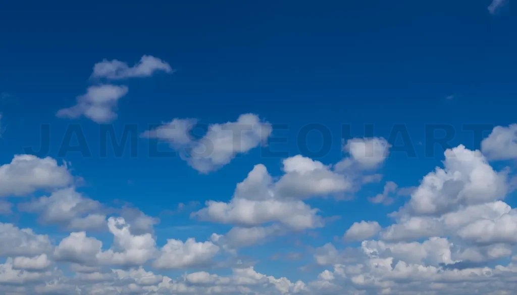 
White cumulus clouds forming on vivid blue sky