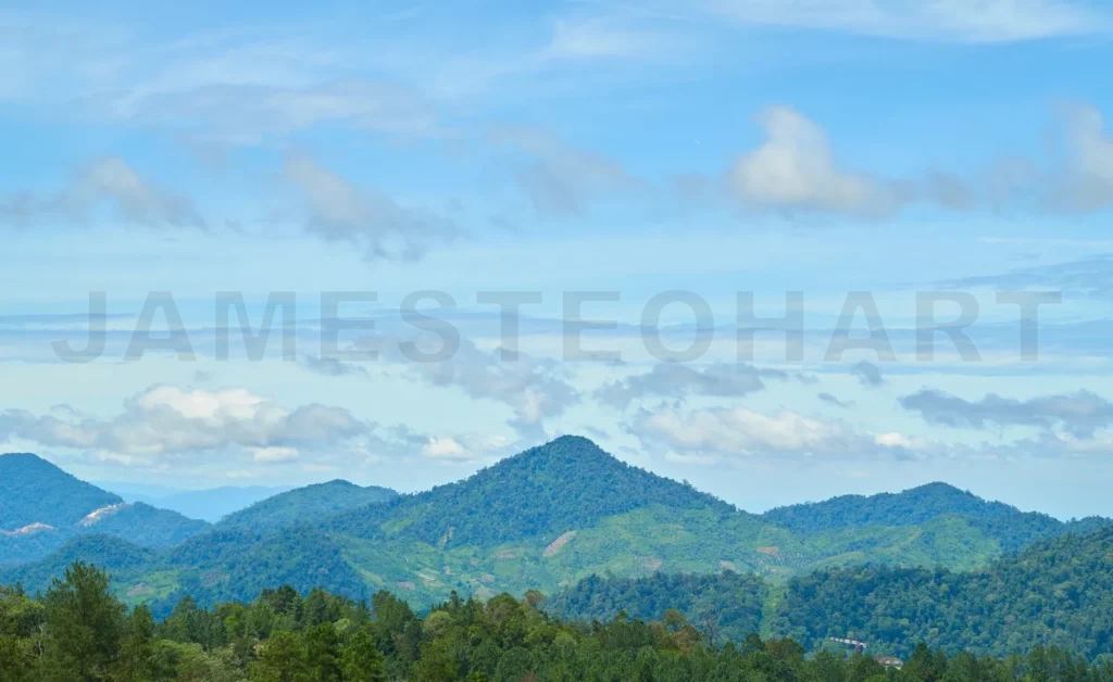 
Layers of lush green mountains filling the frame under a cloudy sky