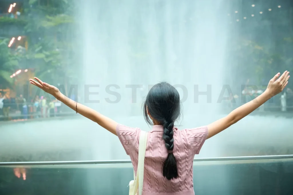 
Young tourist girl embracing the beauty of indoor waterfall in singapore jewel changi airport