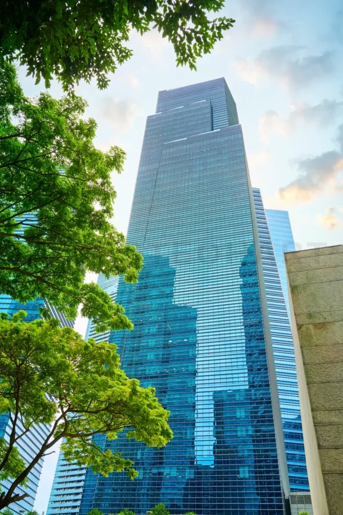 
Modern skyscraper soaring above lush green trees in singapore’s financial district