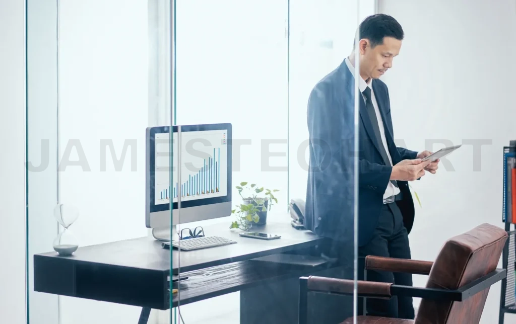 
Asian Businessman In The Office Standing And Using A Digital Tablet To Work
