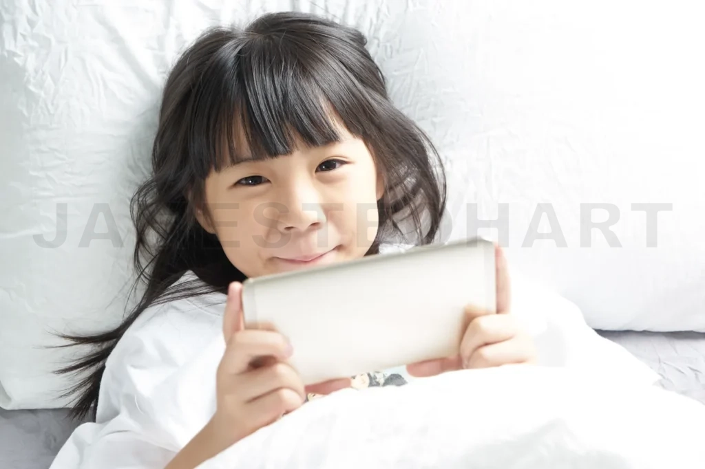 
Little Asian Chinese Girl Using Smartphone And Lying On The Bed
