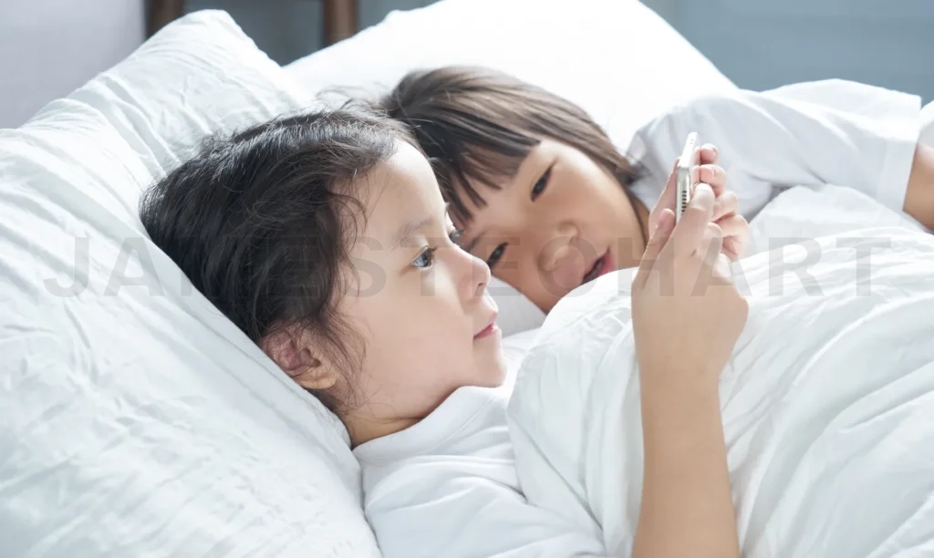 
Two Little Asian Chinese Girl Using Smartphone And Lying On The Bed