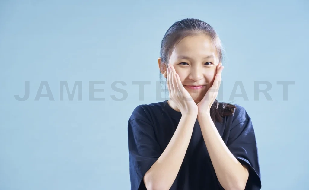 
Young girl smiling with hands framing face