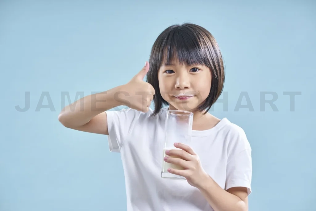 
Young girl drinking milk showing thumbs up
