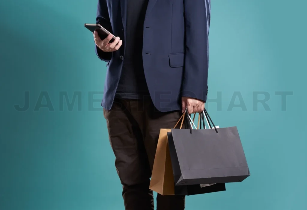 
Close Up Of Man  In Suit Using Smartphone With Shopping Bags , Isolated On Light Blue Background