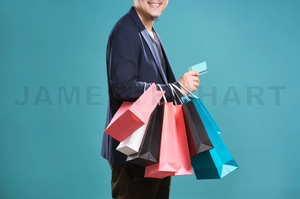 
Close Up Of Man  In Suit Holding Credit Card With Shopping Bags , Isolated On Light Blue Background