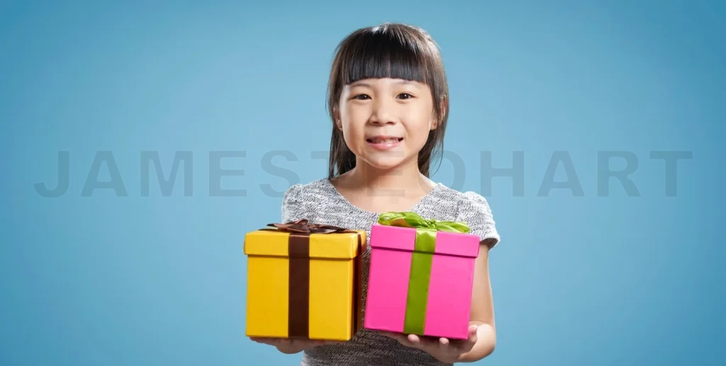 
Smiling young girl holding two colorful gift boxes on blue background