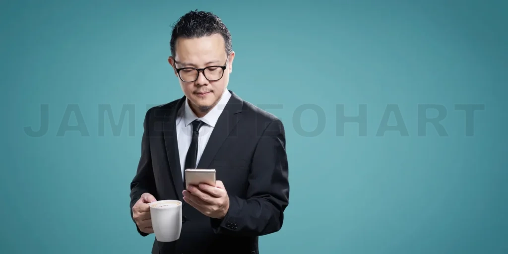 
Businessman checking smartphone with coffee