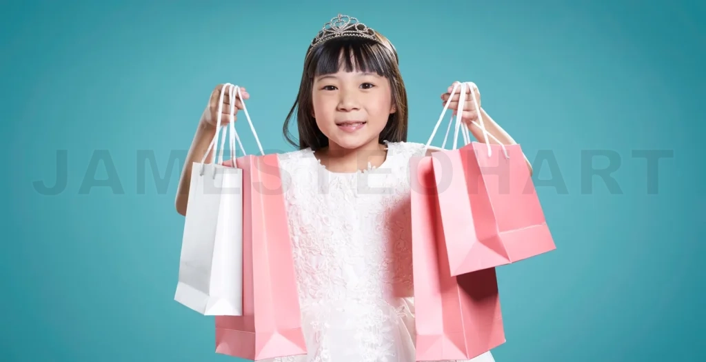 
Smiling girl wearing tiara holding shopping bags on turquoise background