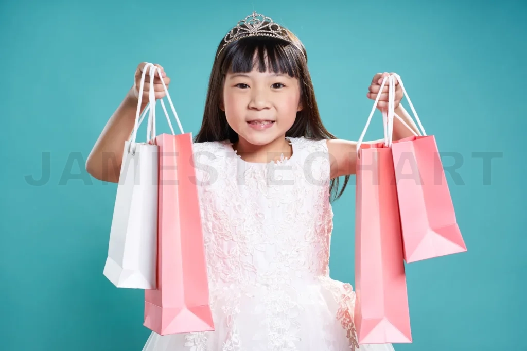 
Close Up Portrait Of Asian Little Happy Girl With Shopping Bags , Isolated On Light Blue Background