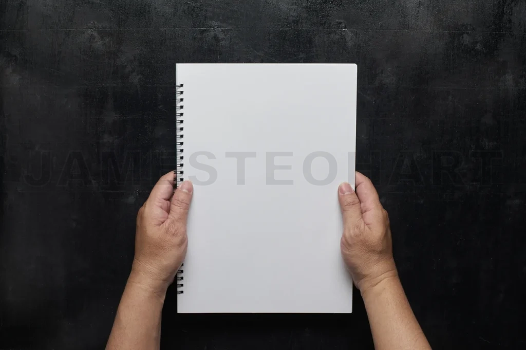 
Wooden Black Office Desk Table With Hand Holding White Blank Notebook