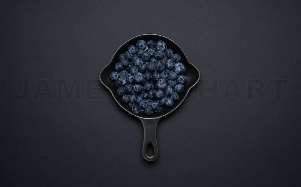 
Blueberries in a dark pan on a grey background