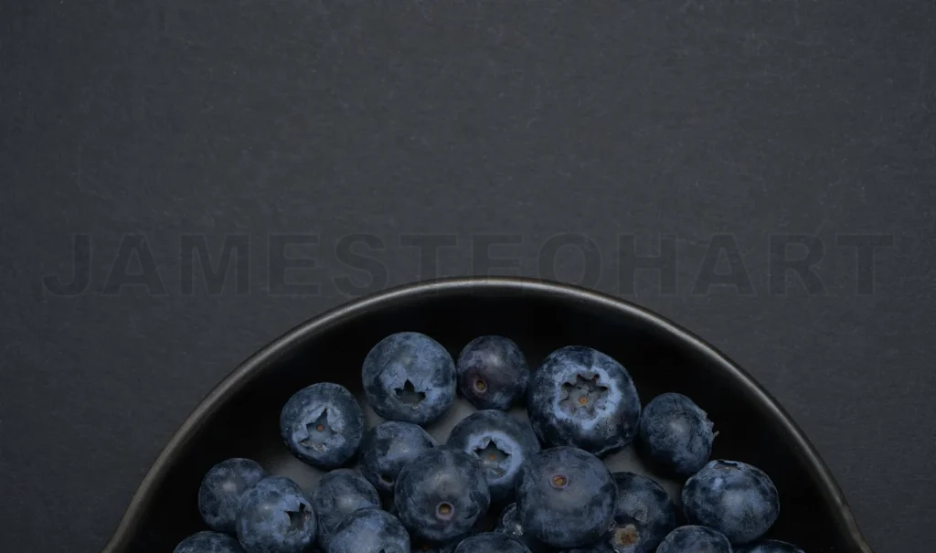 
Fresh blueberries filling black bowl on dark background