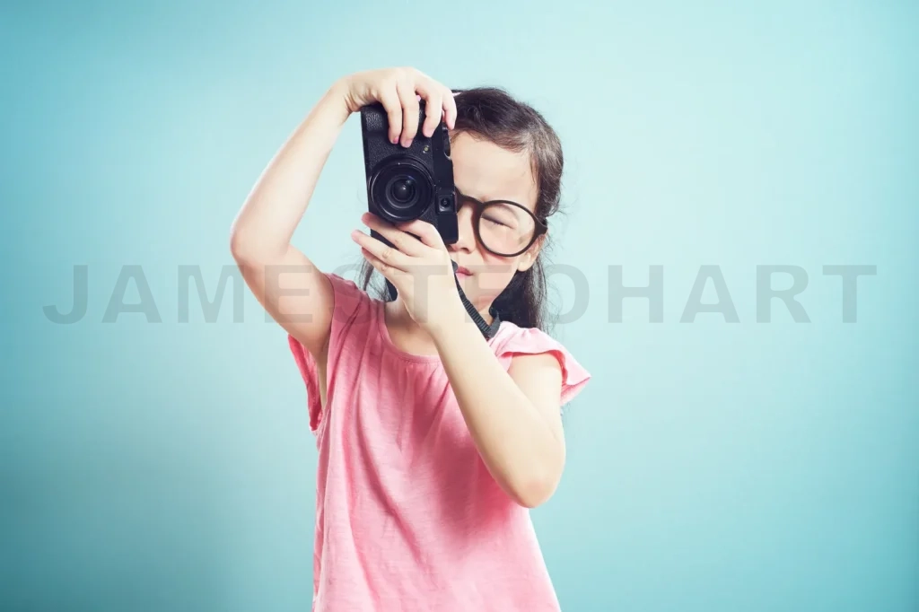 
Portrait Of Cute Asian Little Girl Taking Picture With Retro Camera In The Studio On Vintage Mint Green Background