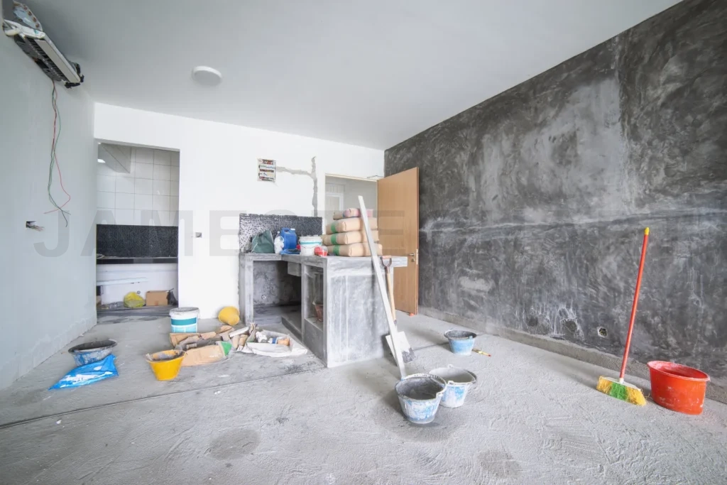 
Construction workers renovating empty room with concrete wall