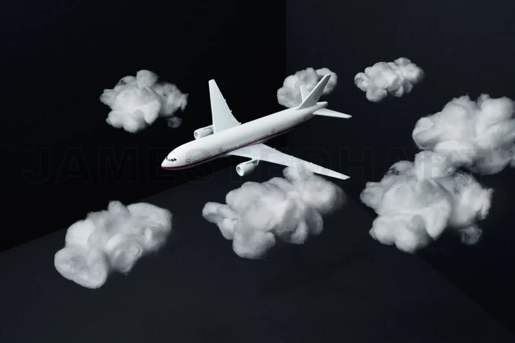 
White toy airplane flying through fluffy cotton clouds