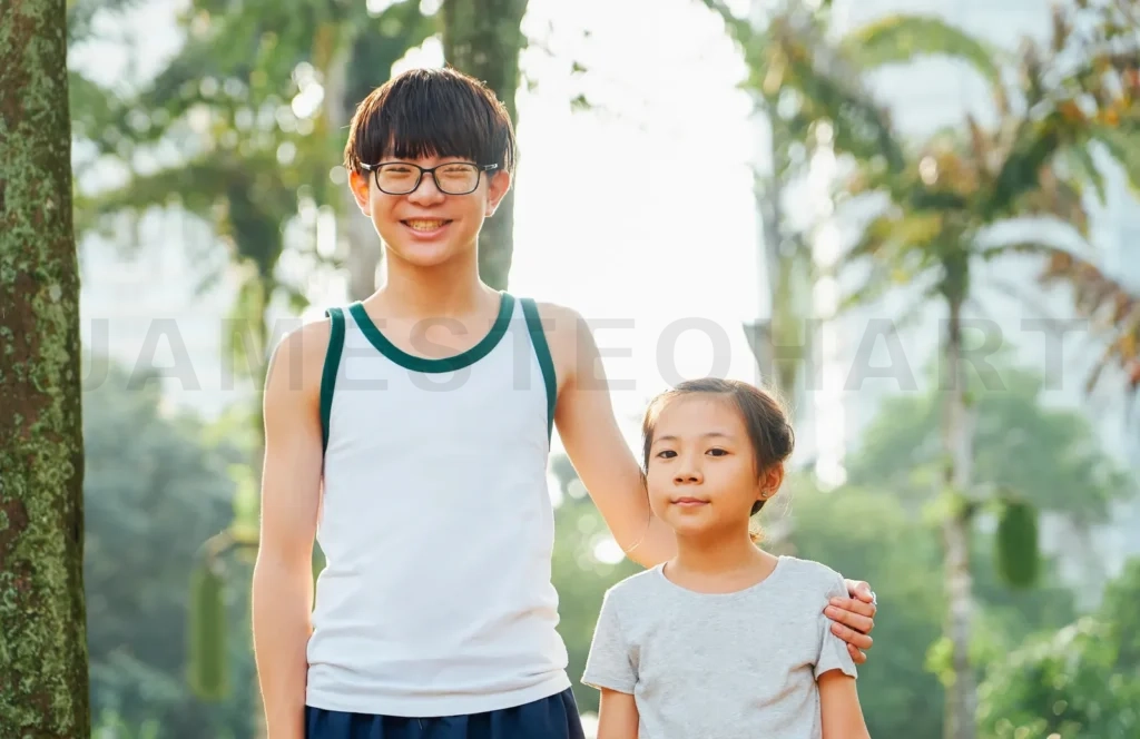 
Asian siblings smiling, bonding outdoors in park