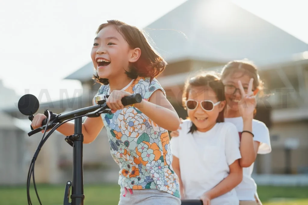 
Happy asian children riding scooter outdoors laughing