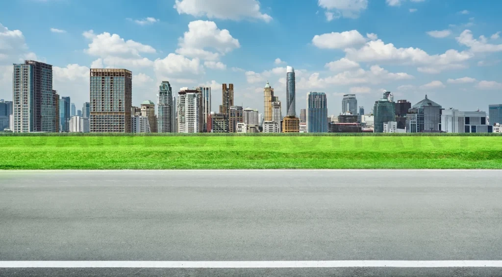 
Panoramic skyline and buildings with empty road and green grass field