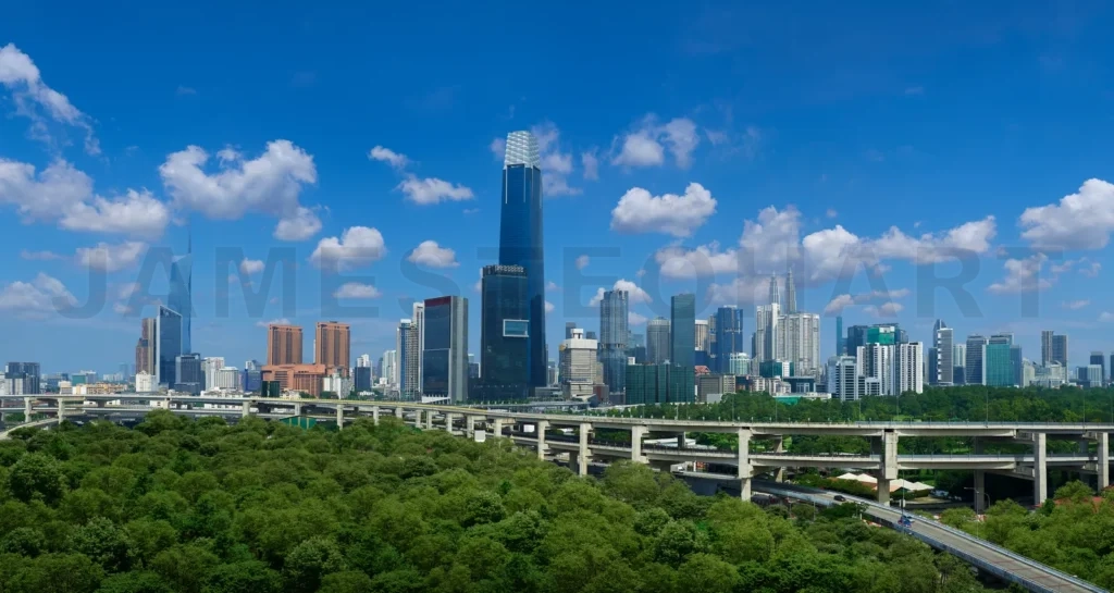 
Kuala lumpur skyline rising above lush green forest and elevated highway on sunny day