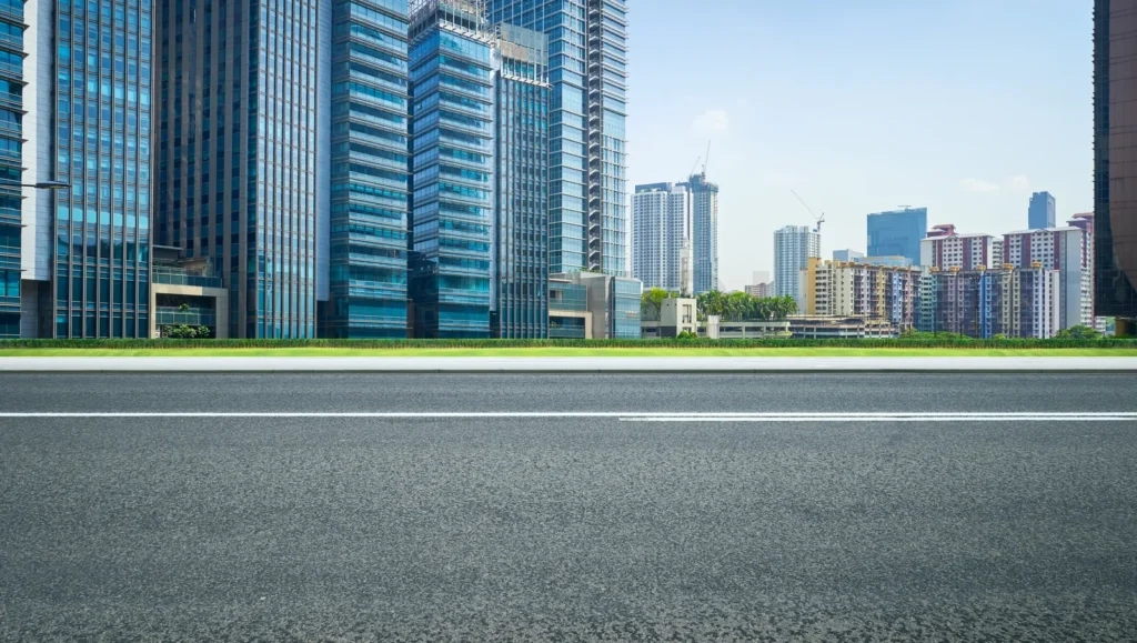 
Empty asphalt road and city skyline at daytime
