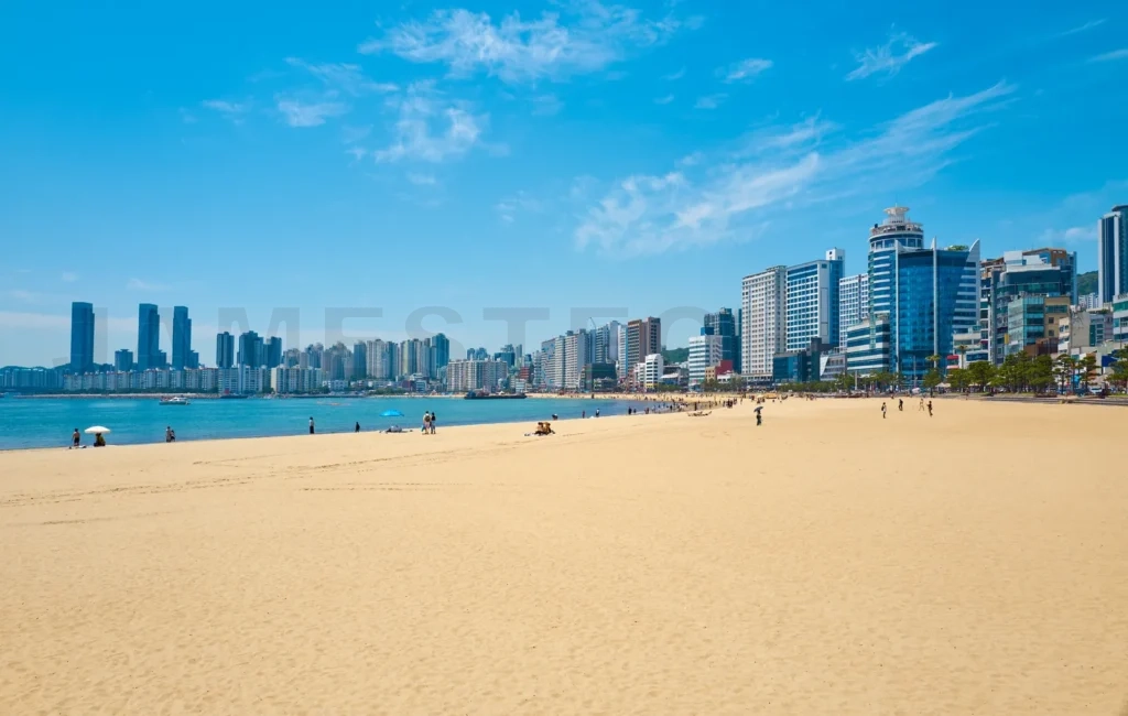 
Busan city skyline rising above gwangalli beach crowded with tou