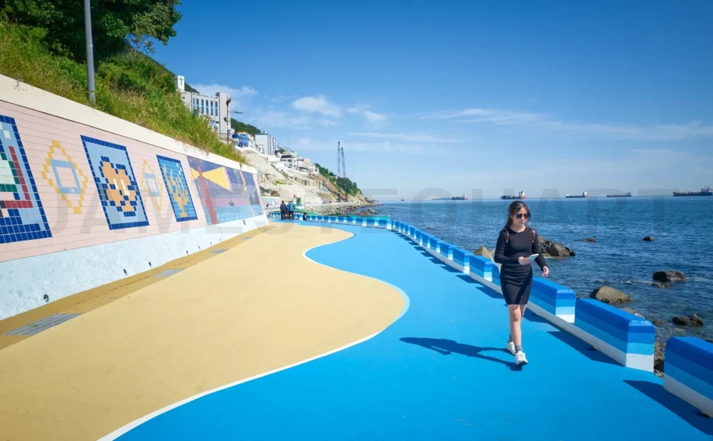 
Woman walking on huinnyeoul culture village coastal path in busa