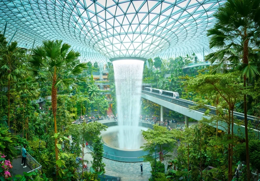 
Jewel changi airport futuristic indoor waterfall cascading in lush green tropical forest