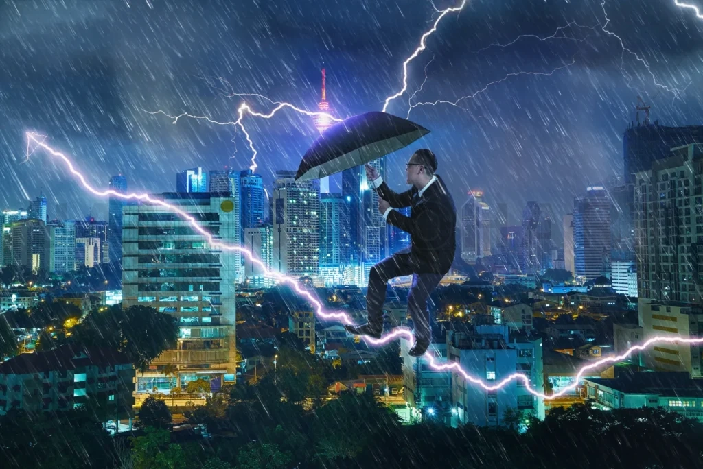 
Young Businessman With Umbrella Against Thunderstorm