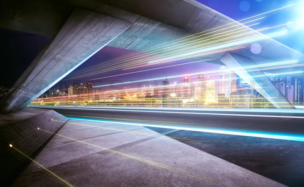 
Empty Asphalt Road Under The Bridge During The Night With Light Trails And Beautiful City Skyline Background