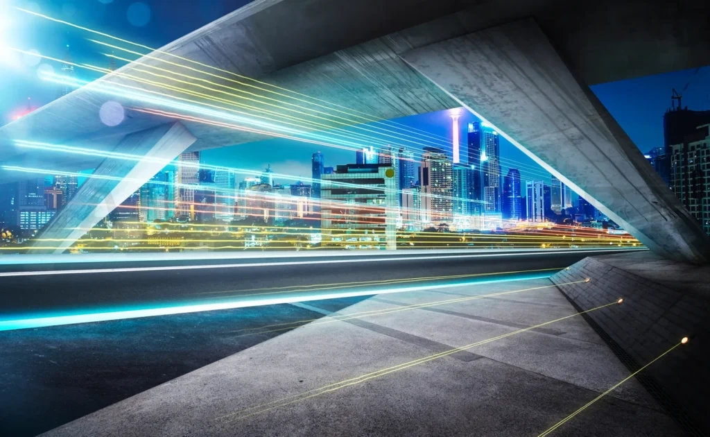 
Empty Asphalt Road Under The Bridge During The Night With Light Trails And Beautiful City Skyline Background